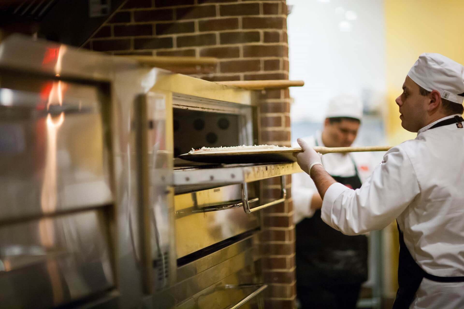 chef putting a pizza in oven